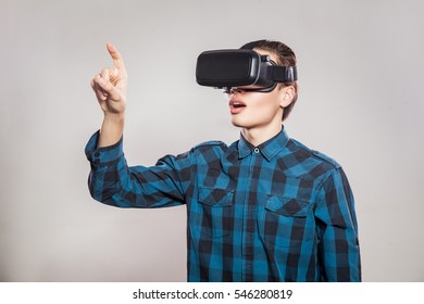 Emotional Funny Man Wearing Virtual Reality Goggles. Studio Portrait Of Video Game Designer Wearing VR Headset. Studio Shot Isolated On Gray Background.