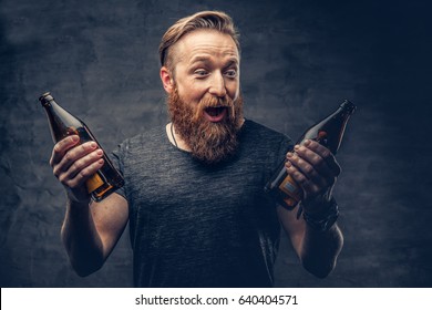 Emotional, funny redhead bearded drunk hipster male holds craft bottled beer.