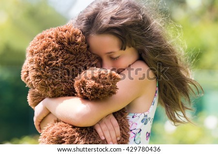 Emotional girl hugging her teddy bear. Young cute girl embracing her brown fur teddy bear. Little girl in love with her stuff toy.
