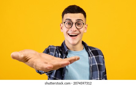 Emotional guy in casual outfit and glasses nerd outstretching big hand at camera, asking for something, posing over yellow studio background, panorama with copy space, creative image - Shutterstock ID 2074597312