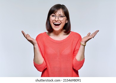 Emotional happy mature woman looking at camera on light studio background