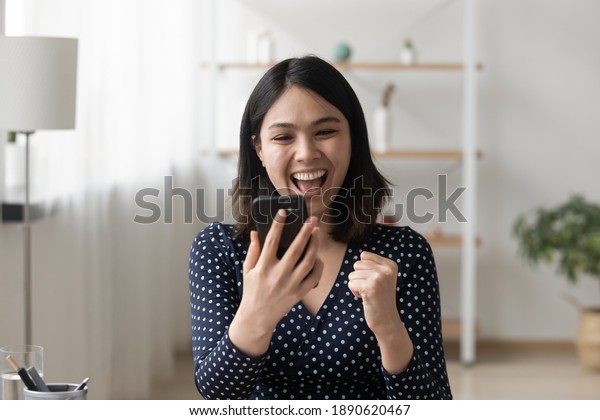 Emotional happy millennial korean ethnicity\
woman looking at smartphone screen, reading message with\
unbelievable amazing news, celebrating getting online shopping\
prize or lottery win\
notification.