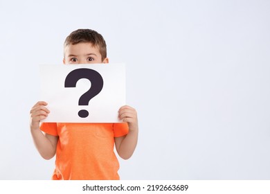 Emotional Little Boy Holding Paper With Question Mark On White Background