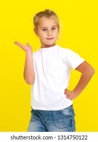 Emotional little girl in a clean white T-shirt. The concept can be used to advertise goods and services, whose logo can be printed on the surface of the shirt.On a yellow background. - Shutterstock ID 1314750122
