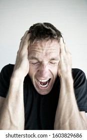 Emotional man in black T-shirt screaming with his hands on his head in frustration - Shutterstock ID 1603829686