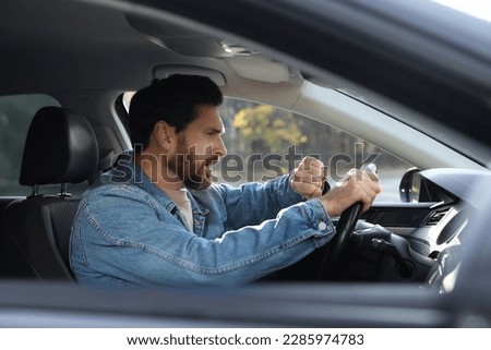 Emotional man checking time on watch in car. Being late concept