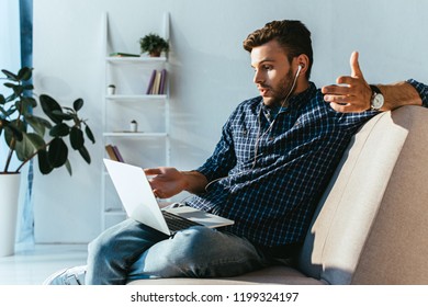 emotional man in earphones taking part in webinar at home