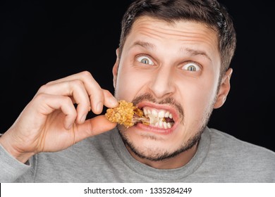 Emotional Man Eating Crispy Chicken Nugget While Looking At Camera Isolated On Black