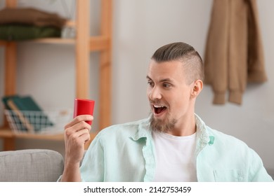 Emotional Man Holding Wireless Portable Speaker On Sofa