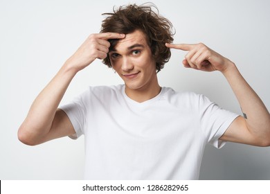 An emotional man with long hair and a white t-shirt shows acne on his face                  