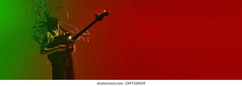 Emotional man, musician with dreadlocks playing electric guitar against gradient red green background in neon light. Concept of music, performance, festival, concert. Banner, ad - Powered by Shutterstock