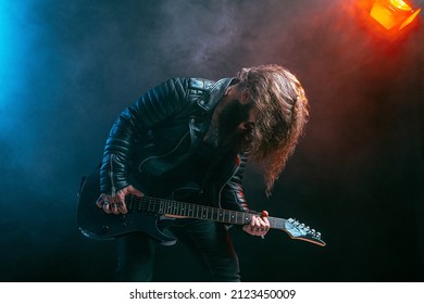 Emotional Man Rock Guitar Player With Long Hair And Beard Plays On The Black Background. Smoke Background. Studio Shot. 