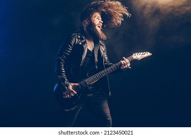 Emotional Man Rock Guitar Player With Long Hair And Beard Plays On The Black Background. Smoke Background. Studio Shot. 