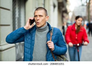 Emotional Man Talking On The Mobile Phone While Walking Outdoors On The Street