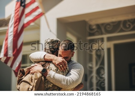 Emotional military homecoming. Female soldier embracing her husband after returning home from the army. American servicewoman reuniting with her husband after serving her country in the military.
