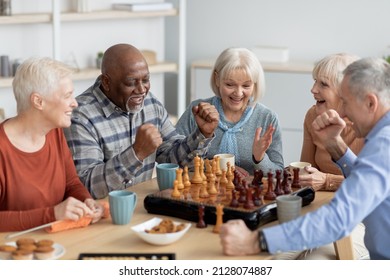 Emotional multiethnic group of senior people playing chess, happy elderly men and women in casual outfits sitting around table with table games, chatting, having fun at sanatorium - Powered by Shutterstock