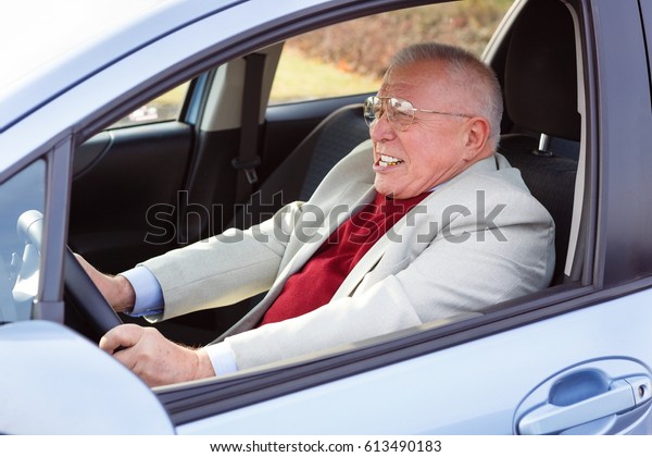 Emotional old senior man driver with\
emotion on the face, gripped the steering\
wheel