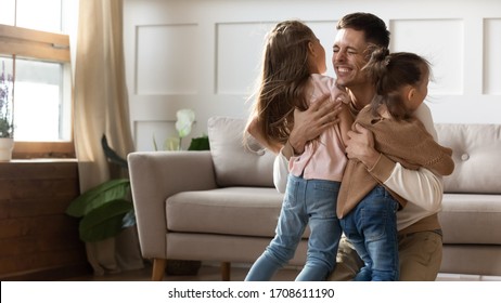 Emotional overjoyed young father cuddling little children siblings, return back home after long time business trip. Happy daddy glad to see small kids sisters after separation, celebrating reunion. - Powered by Shutterstock