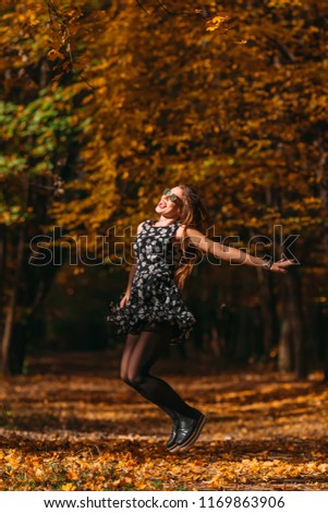 Emotional photo of girl with gorgeous dress jumping in autumn park on sunny day. Walk in the autumn park. Photo in motion.