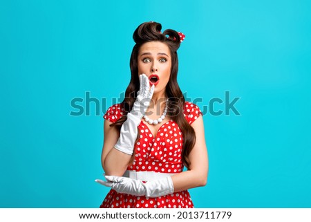 Emotional pinup woman in retro outfit over cannot believe amazing offer or sale, opening her mouth in surprise over blue studio background. Shocking news, promo, advertisement
