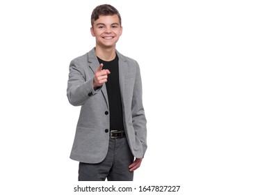 Emotional Portrait Of Handsome Caucasian Teen Boy In Suit Laughing And Pointing Finger To You. Funny Cute Smiling Child 15 Year Old Looking At Camera Choosing You, Isolated On White Background.