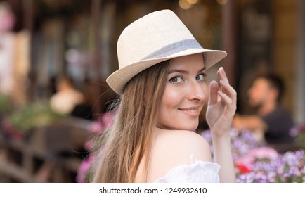 Emotional portrait of a happy and cheerful girl in a hat looking at the camera with her head turned while walking through the summer city. Woman in city& Lifestyle& Positive emotions. Summertime