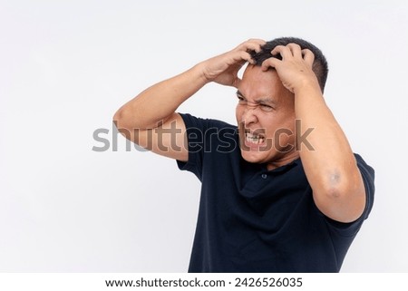 An emotional portrait of a middle-aged man showing intense frustration and anger by gripping his head aggressively against a white background.