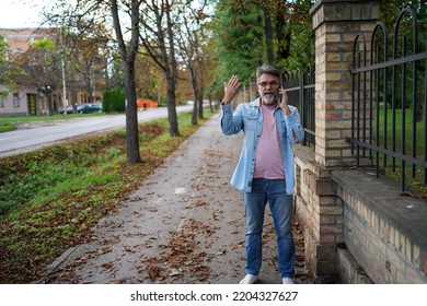 Emotional Portrait Of A Pensive And Attentive Mature European Man In Glasses. Man In Summer City. Business. Smiling Senior Man On A Phone Call In The Park