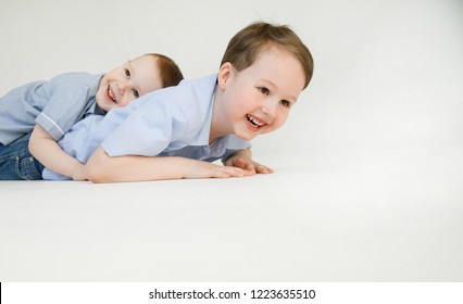 Emotional portraits of mischievous and funny little brothers, playing and dabbling on the floor in a white studio. Happy family. Lifestyle. Childhood. Positive emotions and energy. Happiness life