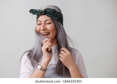 Emotional portraits of a paled long hair asian matured woman on grey background