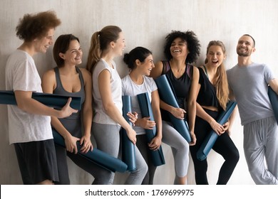 Emotional positive happy young multiracial sporty people feeling excited waiting for yoga training start in modern studio, diverse students enjoying talking relaxing after lesson finish in sport club. - Powered by Shutterstock