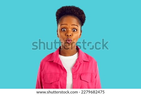 Emotional pretty African American girl looking very surprised. Portrait of amazed, open-eyed young woman in casual pink shirt whistling in surprise. Teenage girl grimacing, human reaction concept