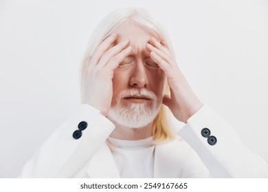 Emotional relief, stress management, businessman with white hair, minimalist background The image shows a man with light colored hair, gently holding his head, expressing a moment of introspection and - Powered by Shutterstock