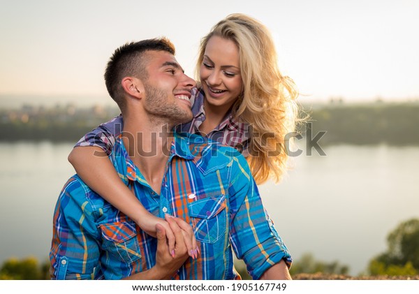 Emotional romantic couple smiling and enjoying\
beautiful day in nature by the\
river