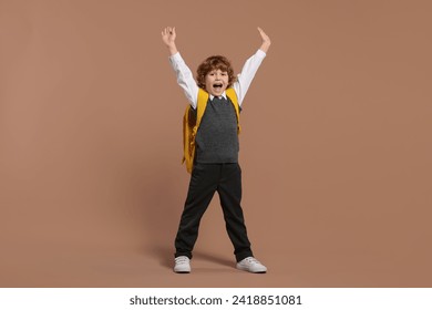 Emotional schoolboy with backpack on brown background - Powered by Shutterstock