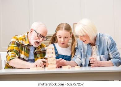 Emotional Senior Couple With Granddaughter Playing Game At Home