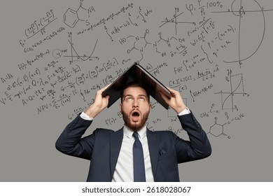 Emotional shocked businessman in suit with laptop on his head on grey background with mathematical equations, formulas and diagrams drawing