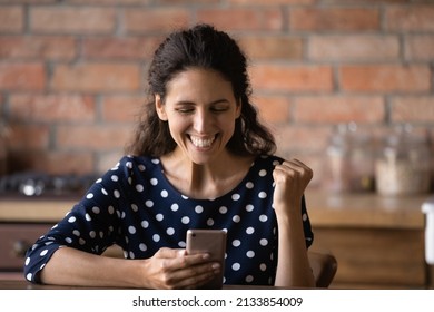 Emotional Sincere Young Hispanic Woman Making Yes Gesture Looking At Smartphone Screen, Celebrating Online Lottery Win Or Good Luck Success In Internet Gambling Auction, Feeling Overjoyed At Home.