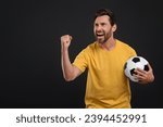 Emotional sports fan with soccer ball on black background, space for text