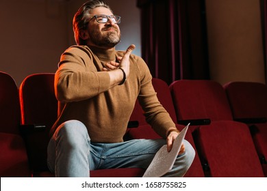 Emotional Stage Director With Scenario On Seats In Theater