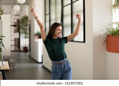 Emotional student girl within walls of institute celebrating successful exam pass, high school or college admission, european employee raised hands feels happy by salary growth, got promoted concept - Shutterstock ID 1613073301