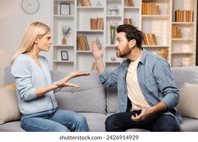 Emotional support for abused families depicted: An enraged husband raises his hand against his wife on their couch, poised to strike - Powered by Shutterstock