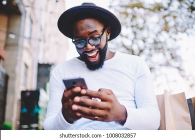 Emotional Surprised African American Guy With Low Prices In Web Store Receiving Message With Promo Code,excited Dark Skinned Hipster Guy In Trendy Hat Overjoyed With Winning Online Contest On Web Site