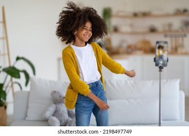 Emotional talented african american school girl broadcasting from home, happy black kid dancing and laughing, looking at smartphone camera, famous kids blogger recording video for followers - Shutterstock ID 2198497749