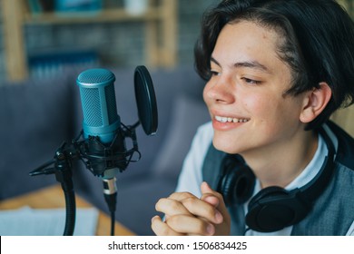 Emotional teenage kid is speaking in microphone in studio recording podcast gesturing expressing opining for online blog. People and modern lifestyle concept. - Powered by Shutterstock