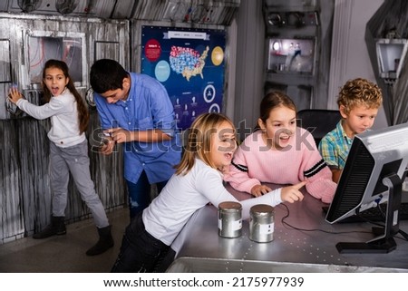 Emotional tween children using computer trying to solve riddles in quest room as underground shelter. Generation Alpha and questomania concept..