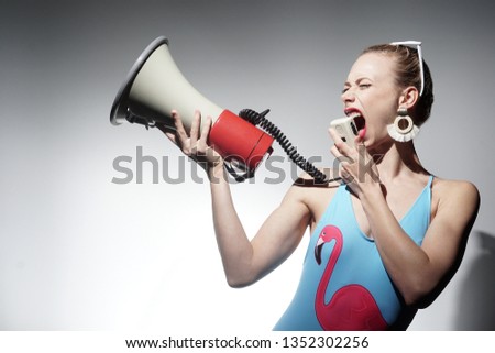 Emotional woman in blue bikini. Concept of a lifeguard . Girl holding in hand megaphone.