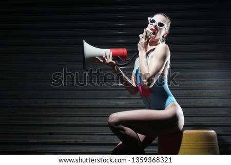 Emotional woman in blue bikini. Concept of a lifeguard . Girl holding in hand megaphone.