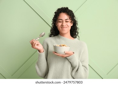 Emotional woman eating tasty cereal rings against color wall - Powered by Shutterstock