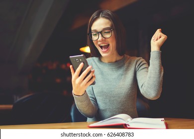 Emotional young attractive female expressing surprise checking email box and reading messages with congratulation of winning using modern smartphone connected to 4G internet in coworking office - Powered by Shutterstock